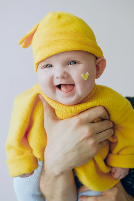 Schilddrüsenunterfunktion Schwangerschaft,Lachendes Baby mit einer gelben Mütze und einem gelben Pullover